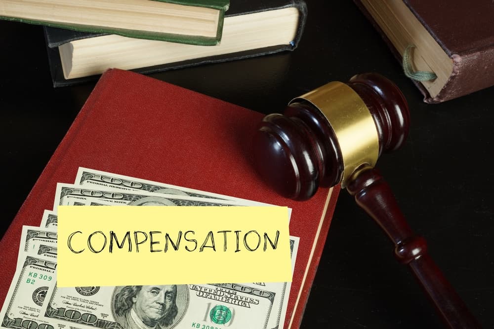 Compensation and judge's gavel. Moral financial compensation for caused damage. Lawyer services and Workers compensation