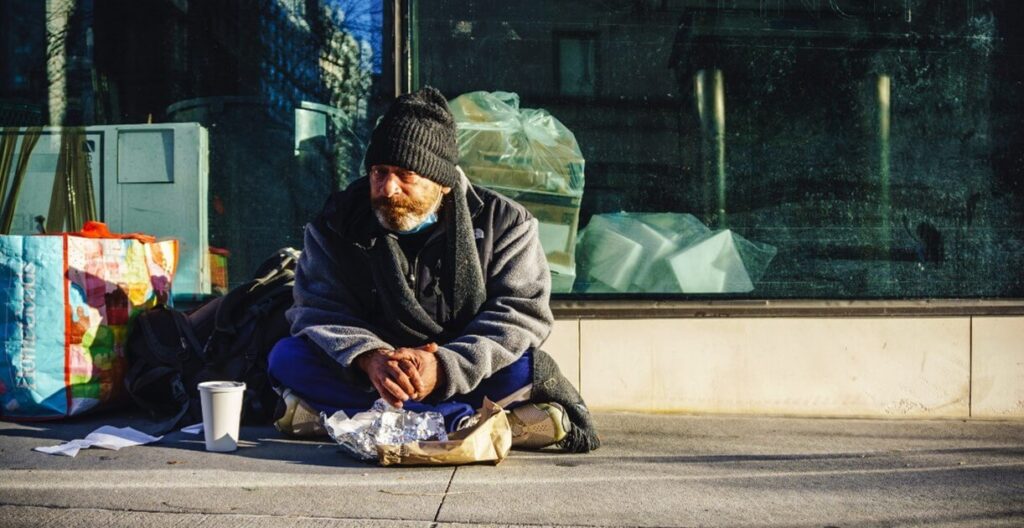 Homeless man sitting on a sidewalk